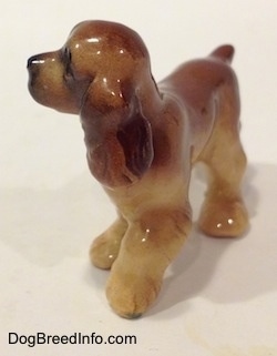 The front left side of a brown and tan ceramic Cocker Spaniel figurine. The figurine is very glossy.
