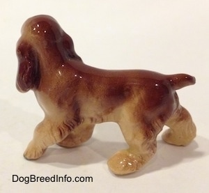 The left side of a brown and tan ceramic Cocker Spaniel figurine. It has a short tail.