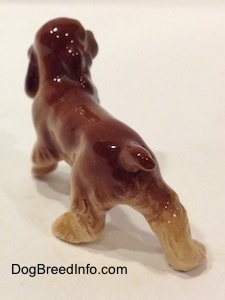 The back left side of a brown and tan ceramic Cocker Spaniel figurine.