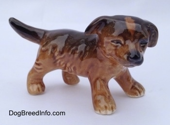 The right side of a brown and black porcelain Aussie puppy figurine. The eyes are very detailed on the figurine.