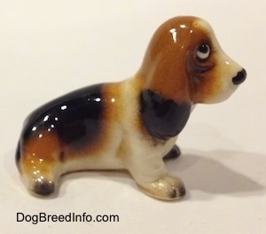 The right side of a black, brown and white ceramic Basset Hound figurine. The figurine lacks fine details.