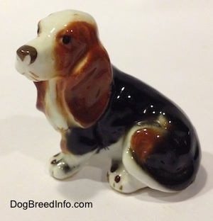 The left side of a brown, black and white ceramic Basset Hound figurine. The figurine is very glossy.