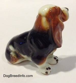 The right side of a brown, black and white ceramic Basset Hound figurine. The ears of the figurine are attached to its side.
