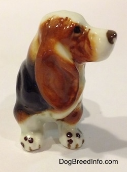 A brown, black and white ceramic Basset Hound figurine. The nose of the figurine has some fine details.