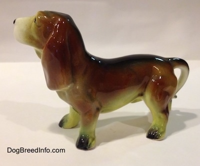 The left side of a brown with white and black ceramic Basset Hound figurine. The figurine has great ear details.