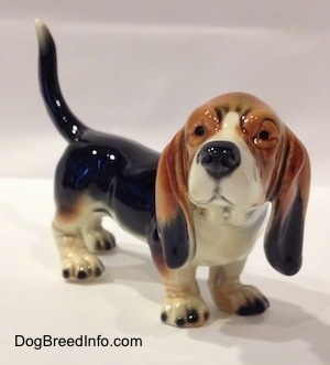 The front right side of a black with white and brown Basset Hound figurine. The figurine is very glossy.