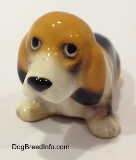 The front left side of a tan and black with white ceramic Basset Hound figurine. The figurine is glossy.