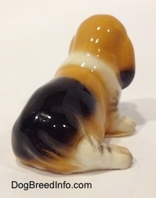 The back right side of a tan and black with white ceramic Basset Hound figurine.