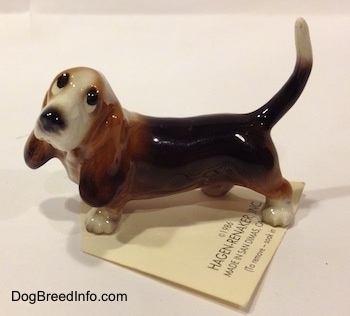 The left side of a black and brown with white Basset Hound figurine. The figurine has black circles for eyes.