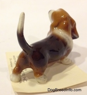 The back right side of a black and brown with white Basset Hound figurine. The figurine is painted well.