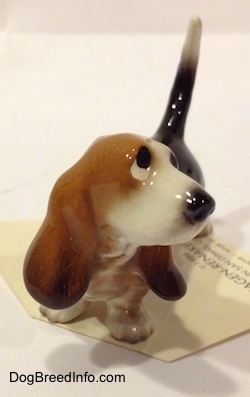 A black and brown with white Basset Hound figurine. The figurine has sad eyes.