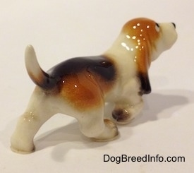 The back right side of a black, tan and white ceramic Basset Hound figurine.