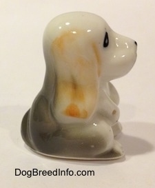 The right side of a white with tan and black bone china Basset Hound puppy figurine. The figurines ear is hard to differentiate from its body.
