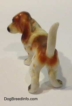 The back of a brown and white porcelain Basset Hound figurine. The figurines tail is in the air.