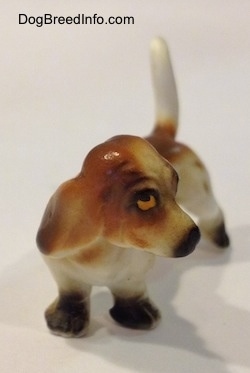 A brown and white porcelain Basset Hound figurine. The eyes of the figurine is detailed.