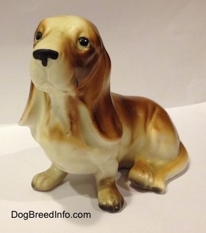 A brown and white porcelain Basset Hound figurine. The figurine is very detailed.