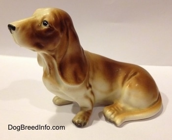 The left side of a brown and white porcelain Basset Hound figurine. The tail of the figurine is very distinguishable from the body.