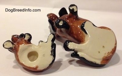 The underside of two, a mother and a puppy, brown and black ceramic Basset Hounds figurines.
