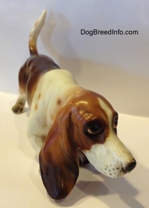 A brown and white porcelain Basset Hound figurine. The figurine has a very detailed face.