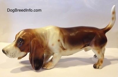 The left side of a brown and white porcelain Basset Hound figurine. The figurine is very detailed.