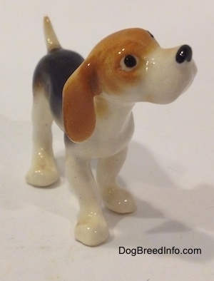 The front right side of a black and white with tan miniature Beagle figurine. The figurine has circles for eyes.