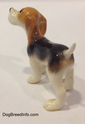 The back left side of a black and white with tan miniature Beagle figurine.