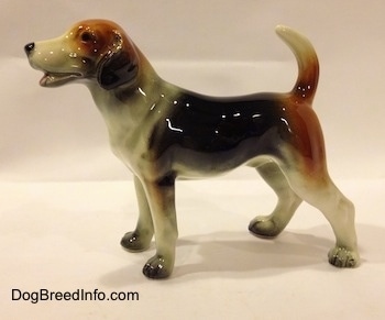 The left side of a black, brown and white Beagle figurine. The figurine is very glossy.