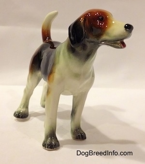 The front right side of a black, brown and white Beagle figurine. The eyes on the figurine is just a black circle.