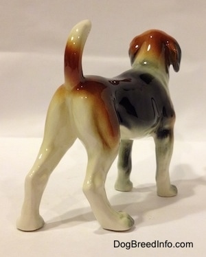 The back right side of a black, brown and white Beagle figurine. The painting on the figurine is great.