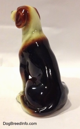 The back left side of a black, brown and white porcelain Beagle figurine. The figurine has a long tail.