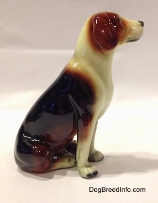 The right side of a black, brown and white porcelain Beagle figurine. The figurine has detailed paws.