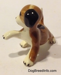 The front left side of a brown, black and white miniature Beagle figurine in a standing pose with its paw up. The figurine has no paw details.