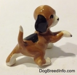 The back right side of a miniature Beagle figurine in a standing pose with its paw up.