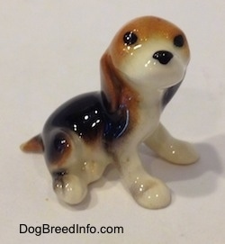 The right side of a black, brown and white Beagle puppy figurine. The figurine has no mouth.