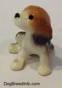 A black, brown and white Beagle puppy figurine. The figurine has circles for eyes.