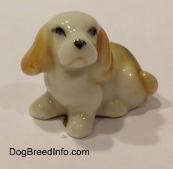 A bone china white with tan and black tiny Beagle puppy figurine. The figurine is very glossy.
