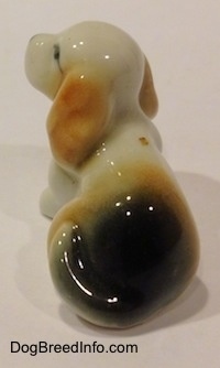 The back left side of a bone china white with tan and black tiny Beagle puppy figurine. The tail of the figurine is indistinguishable from its body.