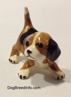 A brown, black and white miniature Beagle in a crouching pose. The figurine is very glossy.