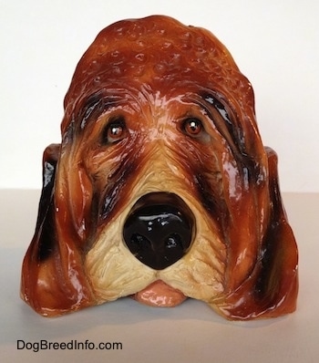 A highly detailed figurine of the head of a Bloodhound dog. The figurine has its tongue sticking out.