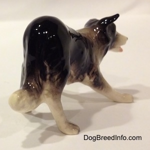 The back right side of a Hagen-Renaker miniature black with white Border Collie figurine. The figurine is play-bowing.