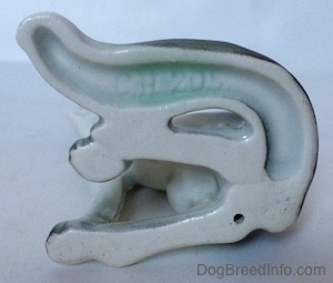 The underside of a white with black Borzoi figurine. The figurine has an engraving that reads - CH 205.