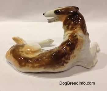 The back side of a brown, white and tan Vintage porcelain Lomonosov Borzoi figurine. The body of the figurine is bumpy.