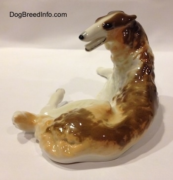 The back right side of a brown, white and tan Vintage porcelain Lomonosov Borzoi figurine. The face of the figurine lacks details.