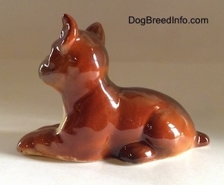 The right side of a brown with white and black Boxer puppy figurine. The figurines paws are attached to its side.