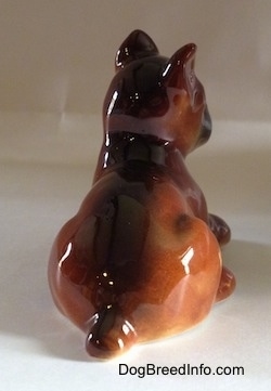 The back of a brown with white and black Boxer puppy figurine. The figurine has a small tail.