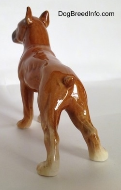 The back left side of a porcelain brown Boxer dog figurine. The figurine has fine paw details.