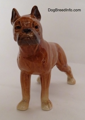 A porcelain brown Boxer dog figurine. The figurine has a detailed face.