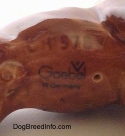 Close up - The underside of a porcelain brown Boxer dog figurine. On the underside is the Goebel W. Germany logo, next to it is a small hole and above it is a series mark that reads - CH 578.