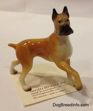The right side of a tan with black and white Boxer mama figurine. The figurine has a detailed black muzzle.