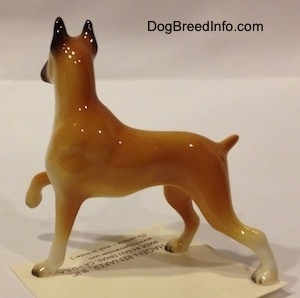 The left side of a tan with black and white Boxer mama figurine. The figurine is glossy.